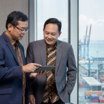 Eksekutif bisnis berdiskusi di kantor dengan pemandangan pelabuhan - ilustrasi strategi ekspor
